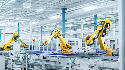 Solpaneler er samlet på en stor produktionslinje med industrirobotarme i en moderne lys fabrik.